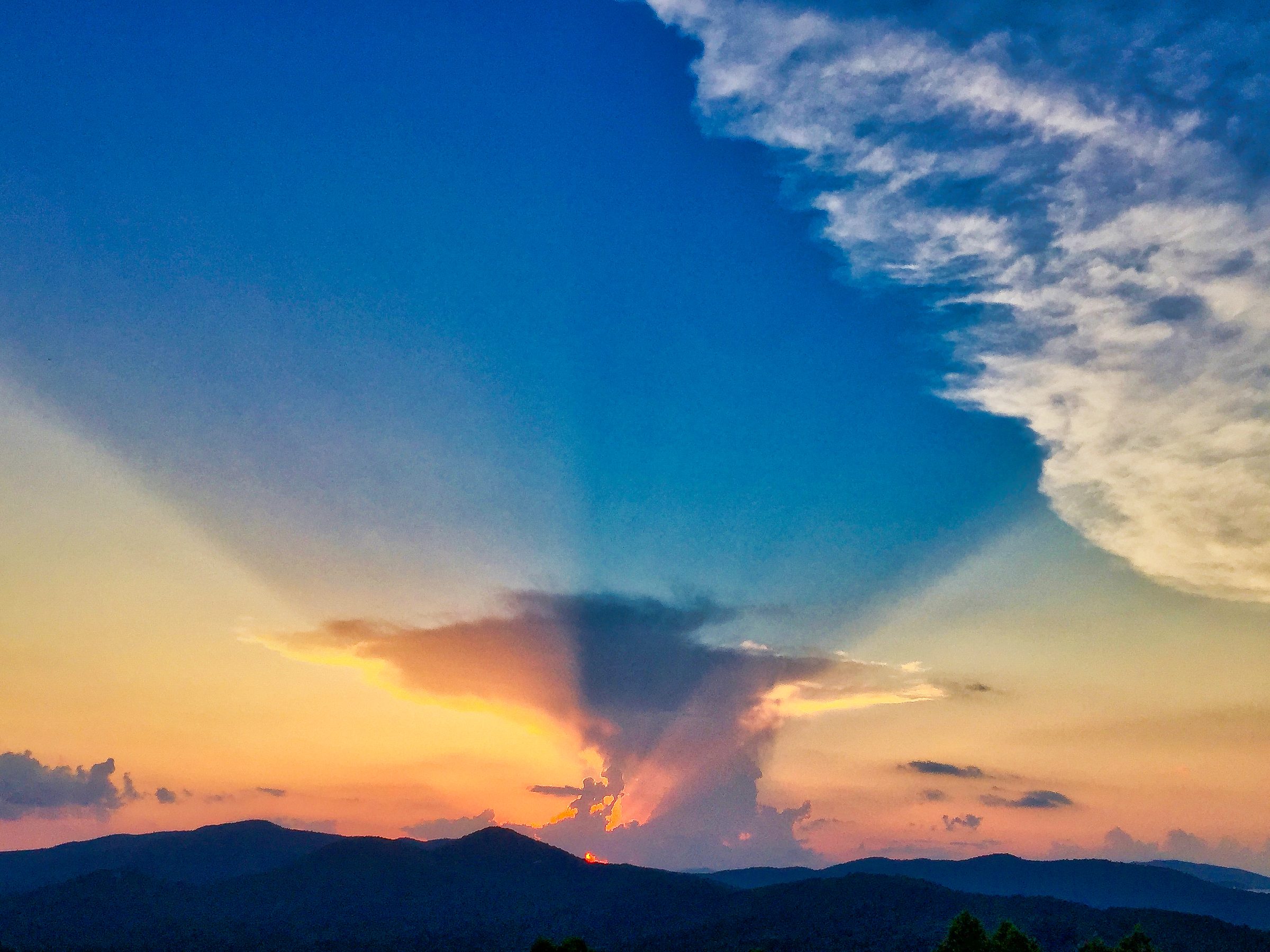 Dramatic storm cloud rays over Blue Ridge mountain silhouette at sunset